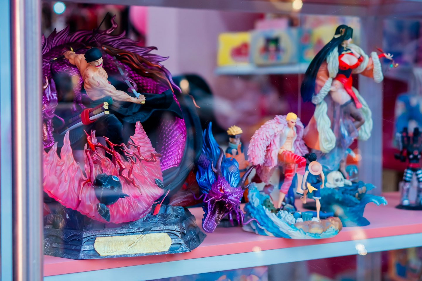 Detailed anime action figures stand inside a glass display case.