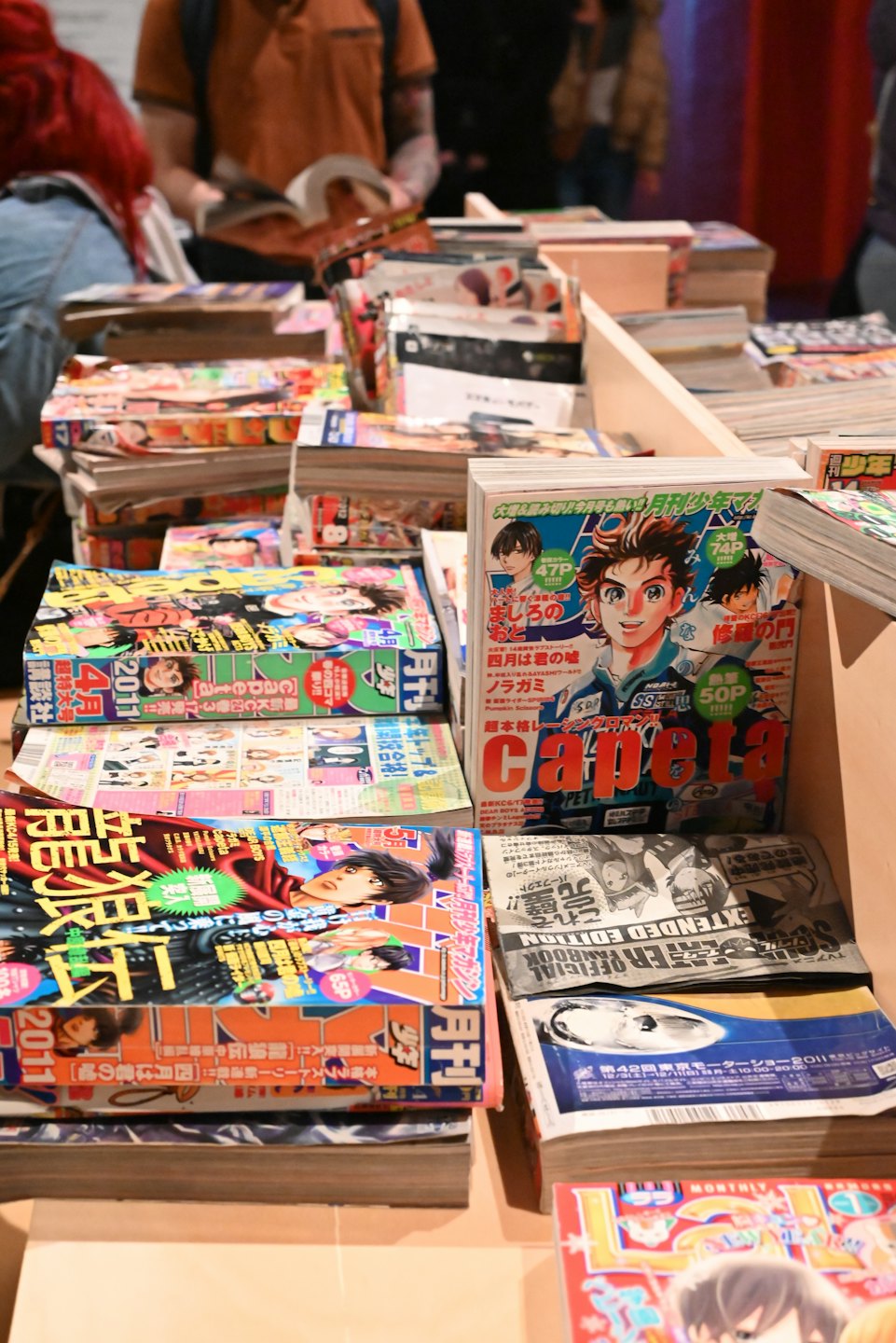 Stacks of manga books and magazines displayed on tables.