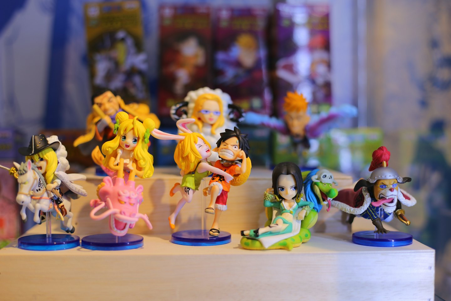 Anime character figurines stand in action poses on a shelf.