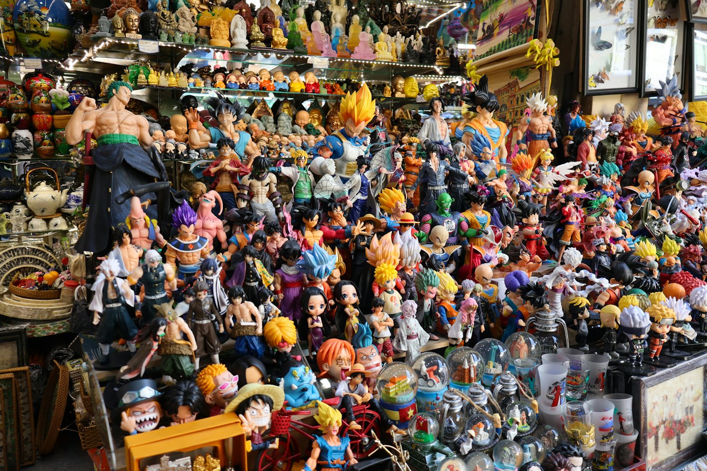 Anime and manga action figures displayed on market stall shelves.